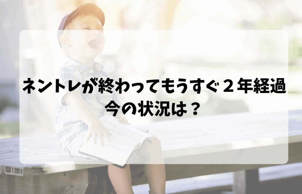 ４歳ぐらいの男の子がベンチに座って本を読みながら笑っている