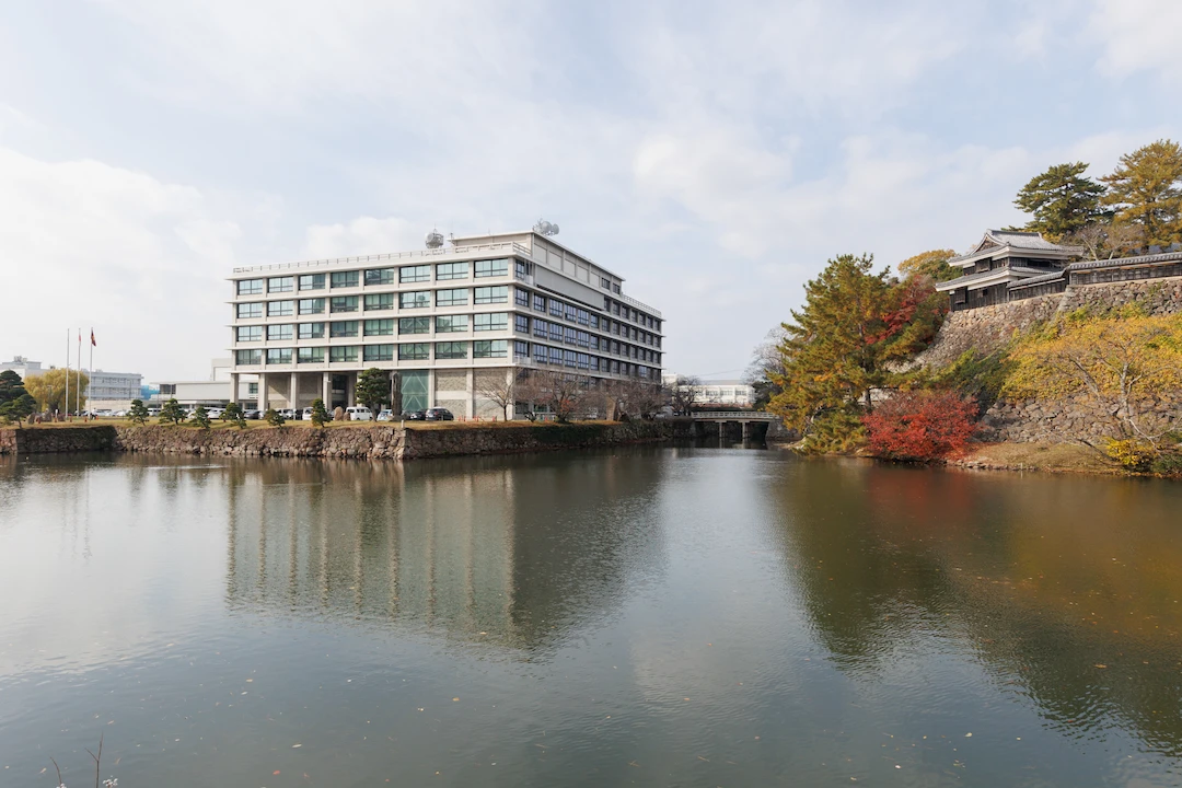 VIVANTの国宝松江城大手前付近。堀の向こうの石垣の上に瓦屋根の建物、左手に白い大きなビル