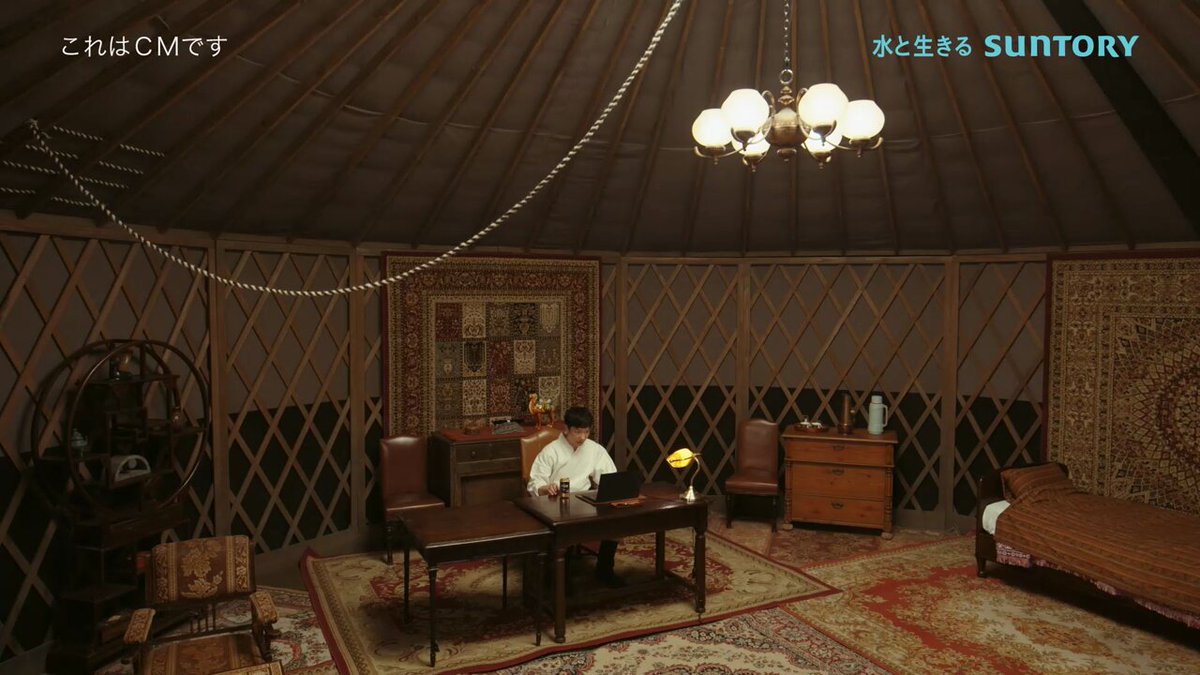 VIVANTのビールの左上に「これはCMです」と入った動画の一場面。丸い天井の部屋で、白い服の人物が机に向かってノートパソコンを開いている