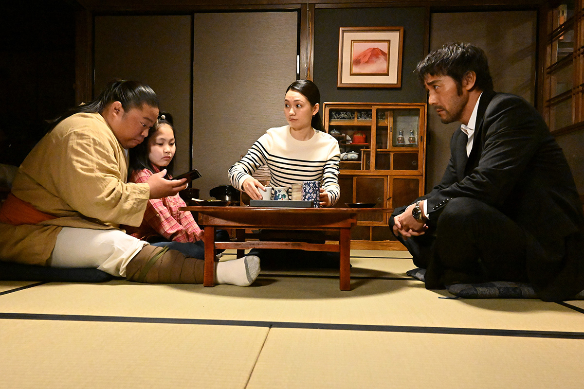 VIVANT第8話の赤い山の絵が掛かった畳の部屋で、4人が低い机を囲んでいる場面