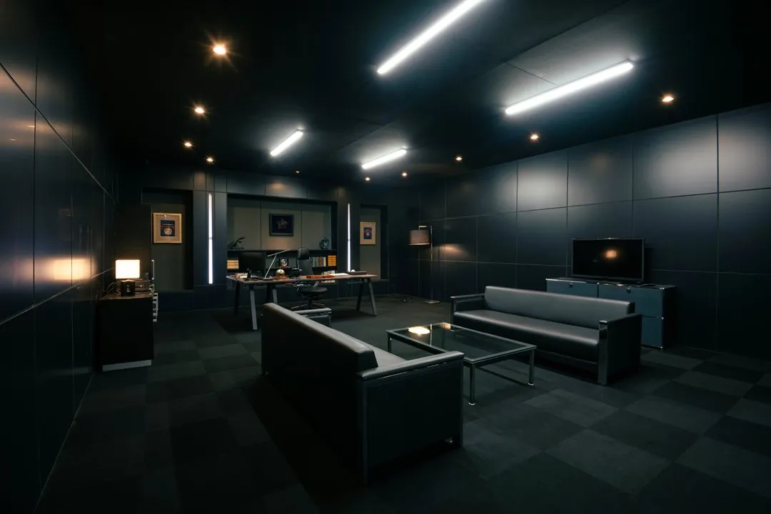 VIVANTのハヤトの黒い壁の部屋に机とソファ、テレビが置かれたVIVANT IMMERSIVE MISSIONの展示エリア