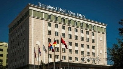 VIVANTのモンゴルの上部に「Kempinski Hotel Khan Palace」の文字がある建物と、その前に並ぶ旗
