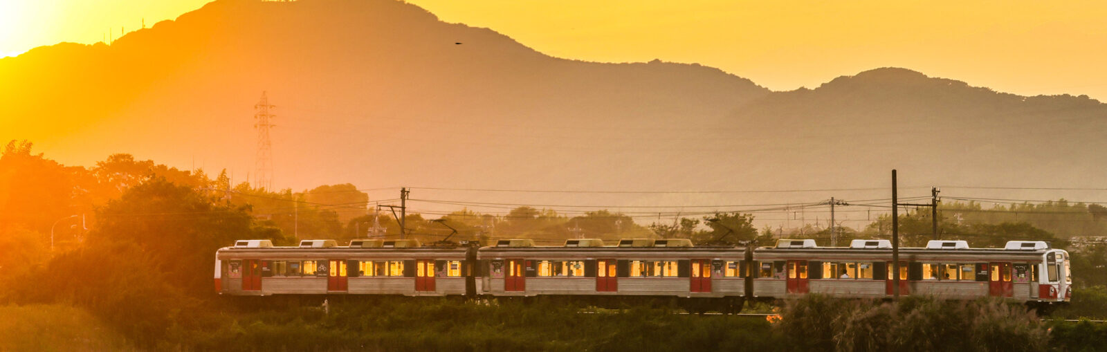 VIVANTの豊橋ロケ地の夕日に染まる山を背にして走る3両の電車