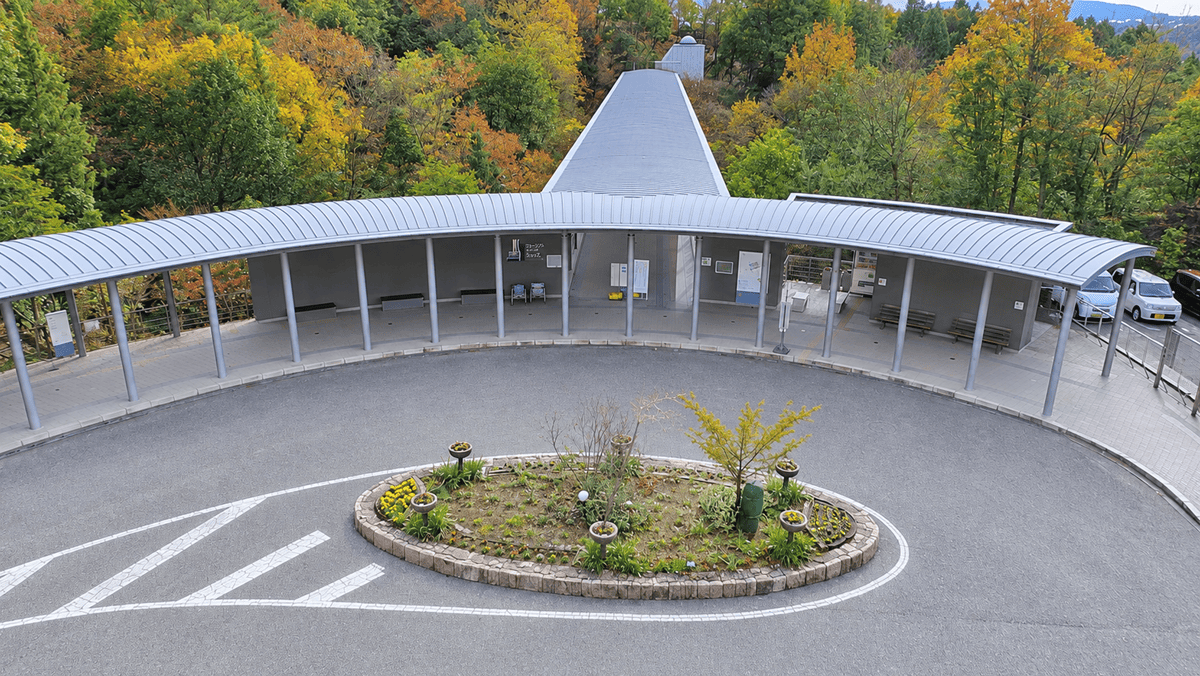 セラミックパークMINOの円形の植え込みを囲む車道と、弧を描く屋根付きの通路