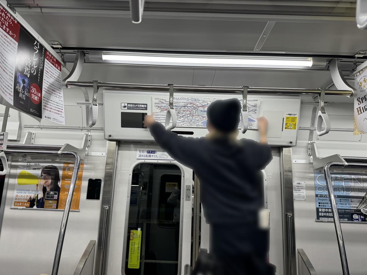 VIVANTのドアの上の路線図の枠に両手を当てている人の後ろ姿
