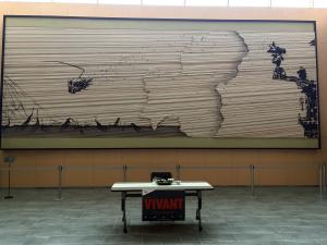VIVANTの壁一面の横長の作品の前に置かれた、VIVANTの赤い札を下げたテーブル